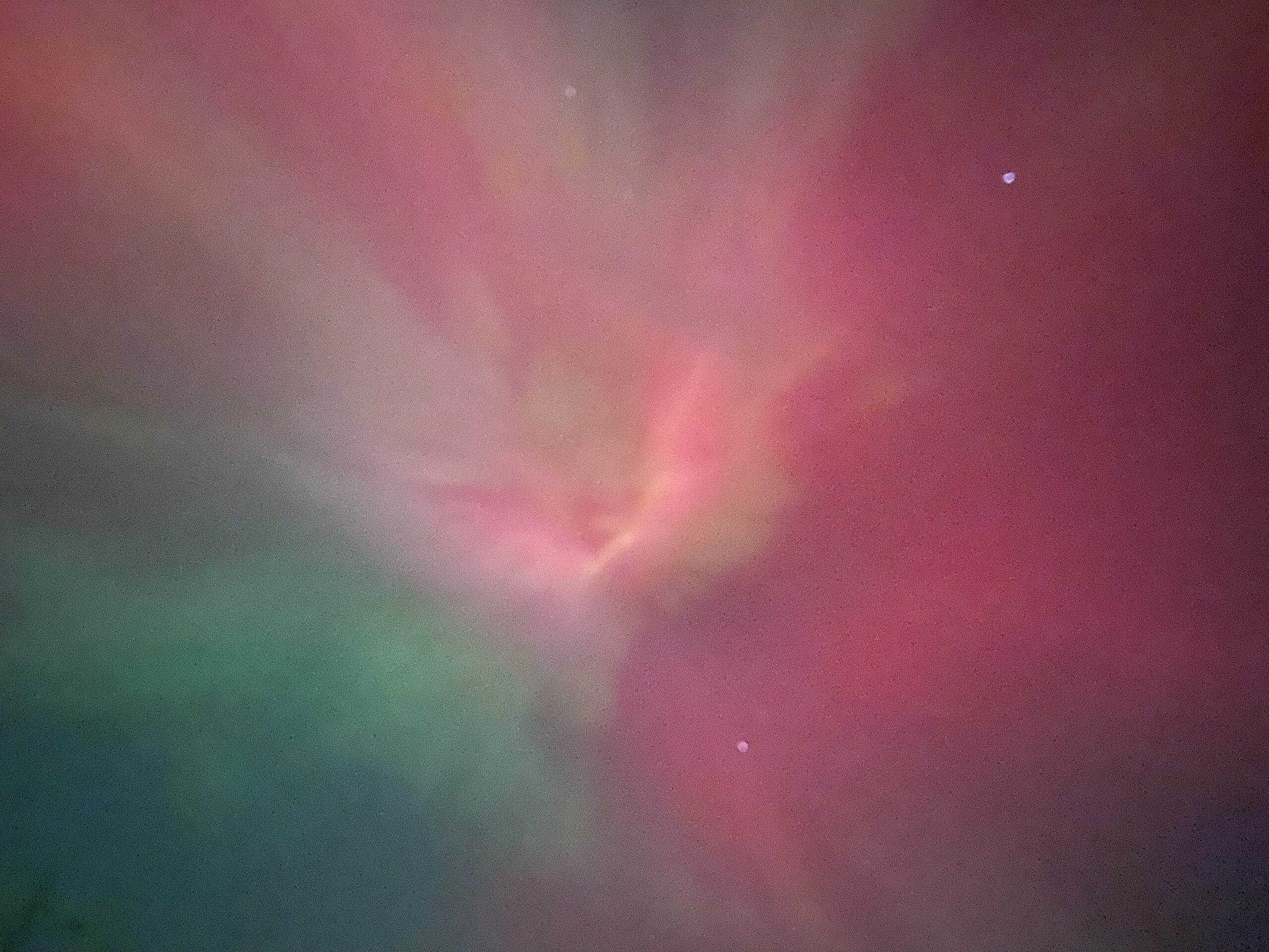 An otherworldly array of reds, greens, and oranges, looking like a portal to another dimension. A couple of stars are visible.